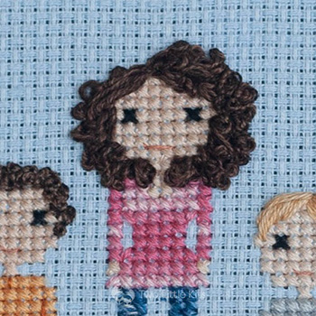 Cross-stitch & embroidery piece depicting a woman with very big, curly hair and a pink ombré shirt.