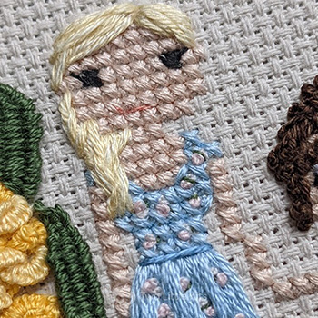 Cross-stitch & embroidery piece depicting a blonde woman in a cute, blue & floral, summer dress.