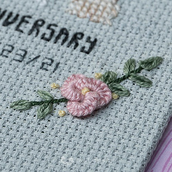 Embroidery piece depicting a tiny, delicate little pink flower using the cast-on stitch