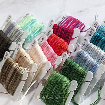A collection of bobbinated DMC variation floss colours scattered in a pile
