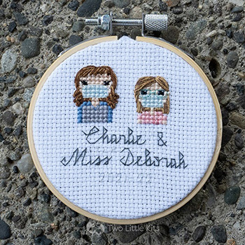 Miss Deborah and Charlie, both cross-stitched wearing face masks in a stitch people style.