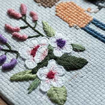 Close up photograph of the flowers next to the man showing a number of different stitches used.