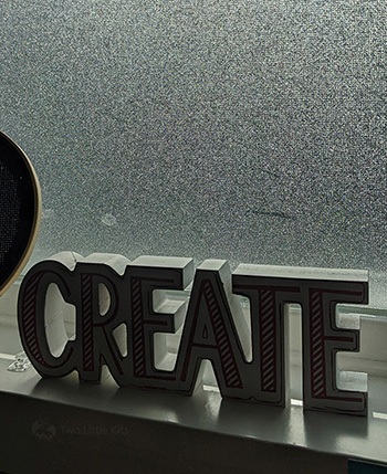 A privacy screen put up on my office window. Infront of it is a painted, wooden sign that says 'CREATE'.