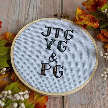 Three rows of initials in a 5in hoop. It reads from top to bottom: JTG, YG & PG all done in cross-stitches.