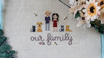 A stitch peple piece with two people, three cats and one dog. There is a large 