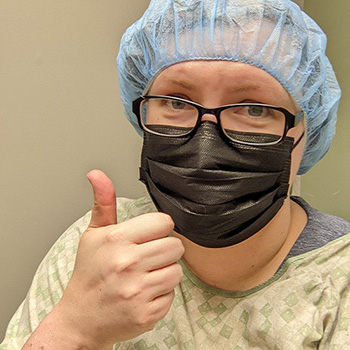 A selfie of Kate post-surgery doing a thumbs up action with her hand.