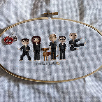 A work-in-progress of a stitch people piece of 5 people and one dog - all the people are in martial arts clothing.