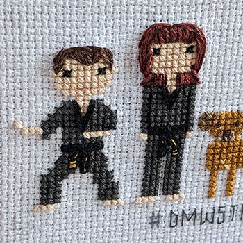 A cross-stitch where you can see both a man and a woman wearing their uniforms. The woman has striking dark red hair and the man is in a fighting stance.