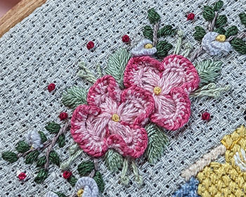 A close-up photograph of the left-side florals of the piece in question. The florals are done with hand embroidery.
