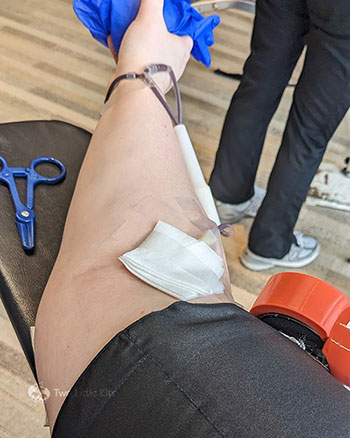 A weirdly angled photo of Kate's arm that is actively donating blood. You can't see the injection site but it's obvious what's happening.
