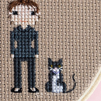 A stitched woman and cat on brown fabric 