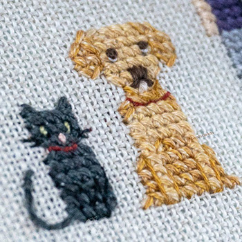 A cross-stitched dog and cat both sitting facing forward