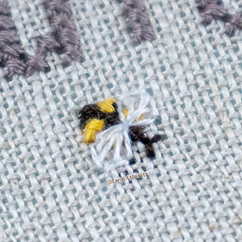 One very small cross-stitched bee.