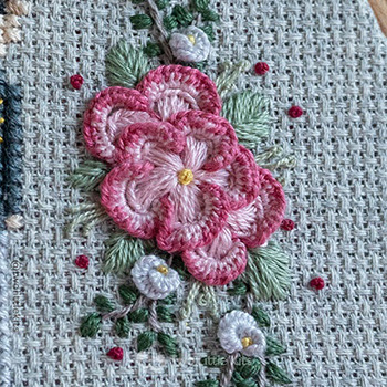 Photo of hand embroidered florals. There are a lot of different stitches being used for this section and the piece is very intricate.